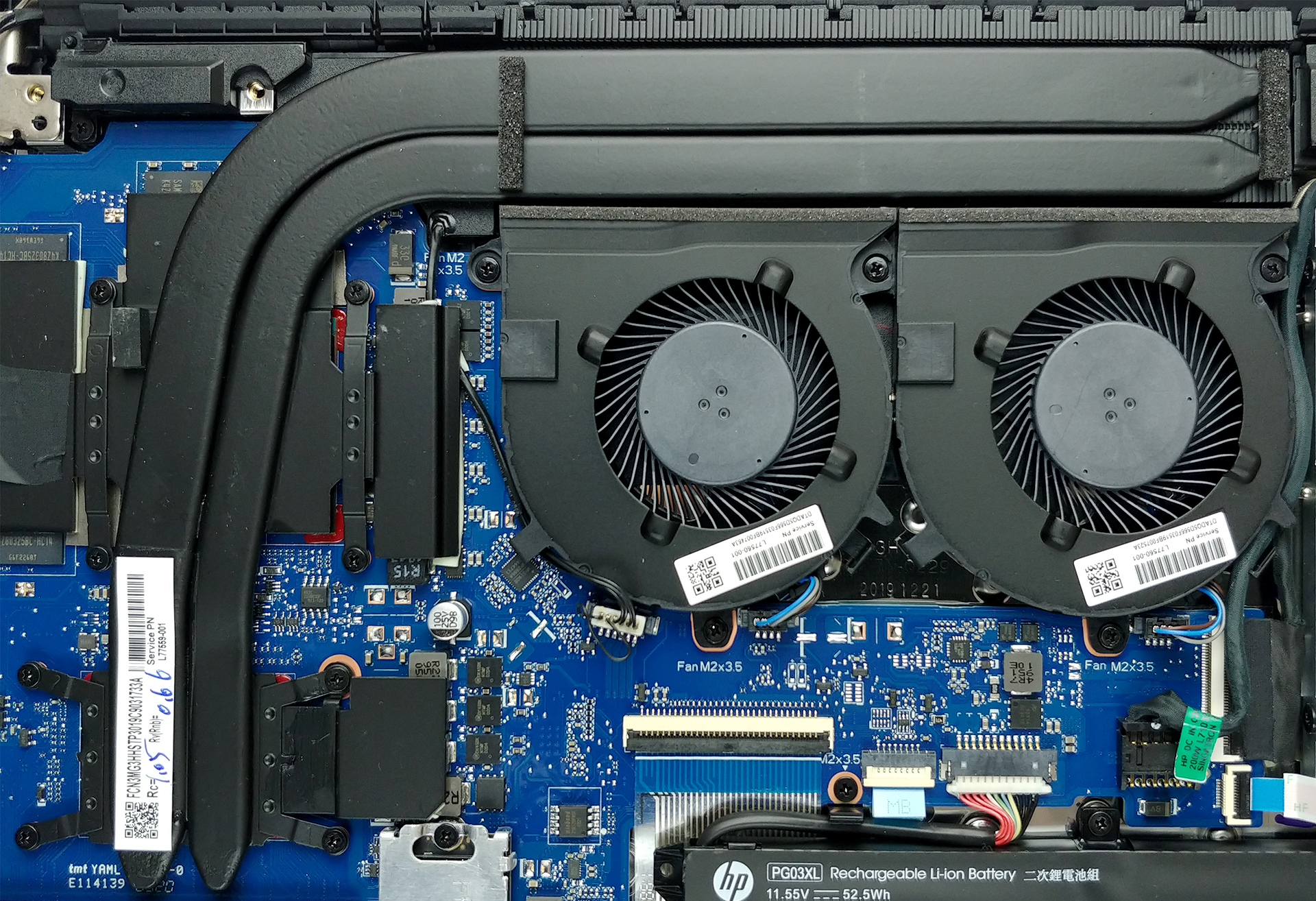  The image shows the internal components of a HP gaming laptop, including the cooling fans, battery and motherboard.